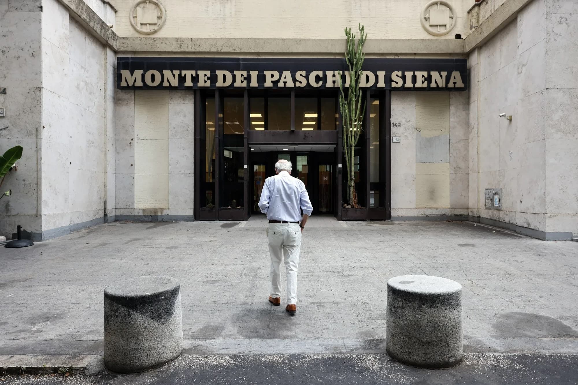 A man seen from behind walking toward the Monte dei Paschi di Siena headquarters entrance
