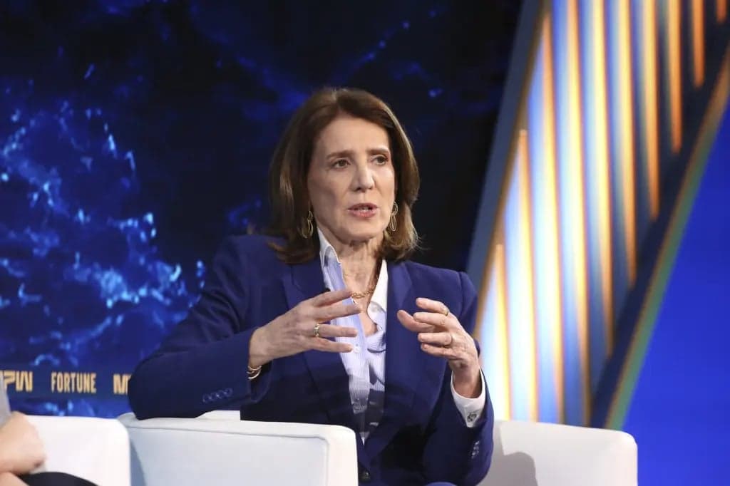 Ruth Porat, wearing a navy blazer, gestures with both hands while speaking during an interview on stage at a Fortune MPW event
