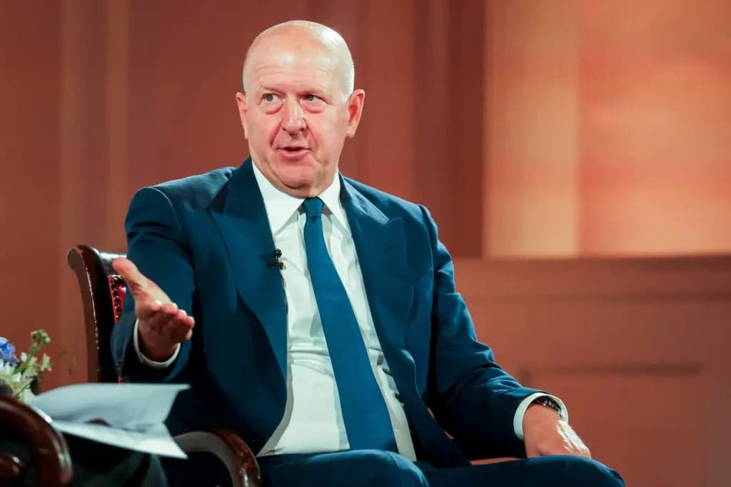 David Solomon, wearing a navy suit and tie, gestures with one hand while speaking during an interview