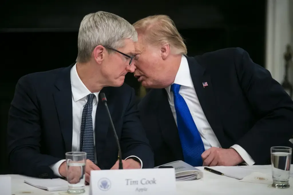 Tim Cook leans in to speak closely with President Trump at a White House meeting, a nameplate reading Tim Cook, Apple, on the table in front of them