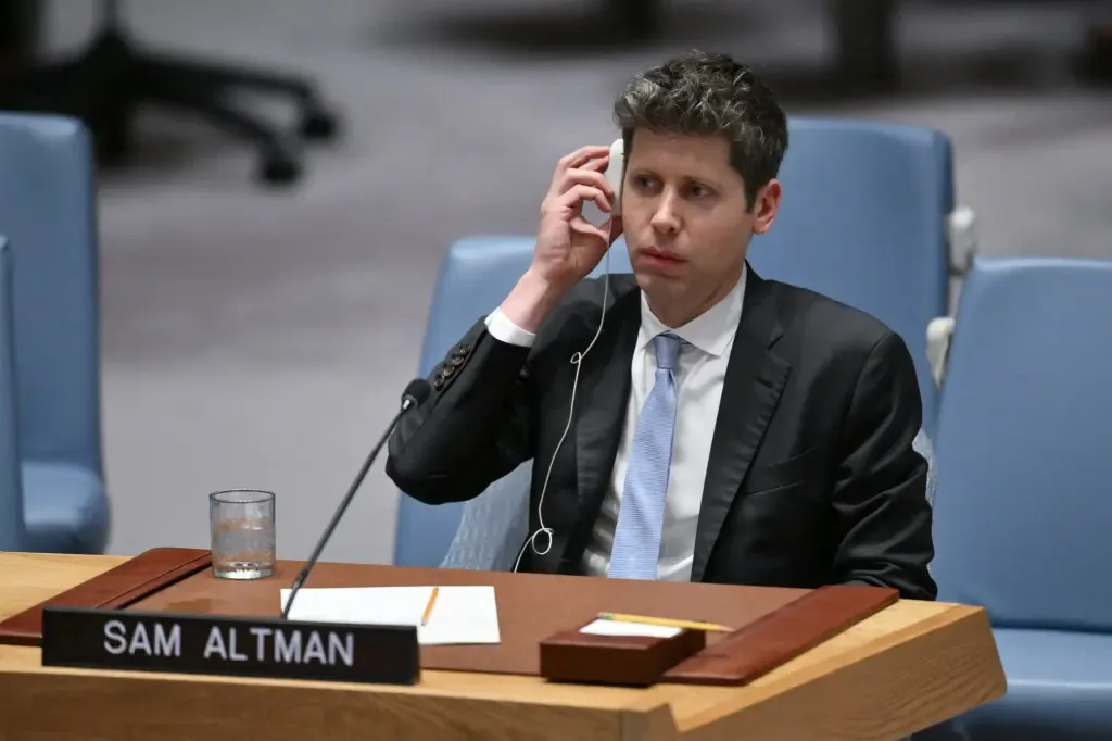 Sam Altman, wearing a dark suit and light blue tie, adjusts an earpiece while seated behind a nameplate reading Sam Altman during a UN Security Council session